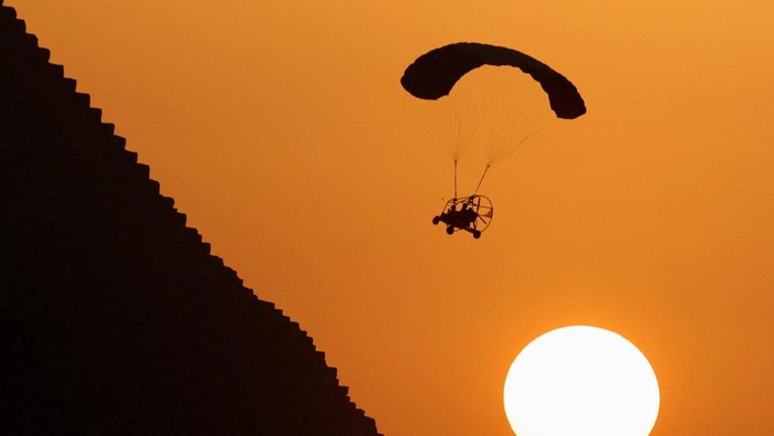 Serunya, Paramotor di Atas Piramida Giza A man flies a paramotor above the Pyramids, in Giza, on the outskirts of Cairo, Egypt, June 16, 2023. REUTERS/Mohamed Abd El Ghany