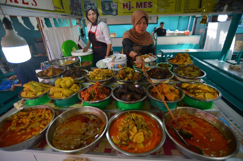 Pedagang menyiapkan nasi kapau pesanan pengunjung di Los Lambuang Bukittinggi, Sumatera Barat, Minggu (18/6/2023). Kawasan Los Lambuang yang merupakan lokasi wisata kuliner di kota Jam Gadang itu ditetapkan pemerintah daerah setempat sebagai zona dengan kuliner yang memenuhi kriteria halal, aman, dan sehat. ANTARA FOTO/Iggoy el Fitra/YU