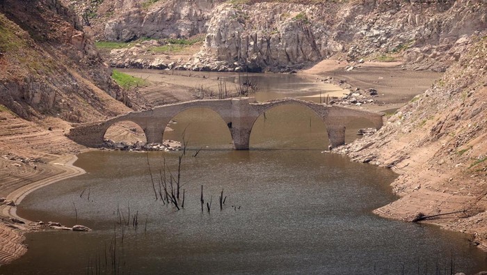 Jembatan Purba Muncul dari Waduk yang Mengering di Spanyol Queros medieval bridge emerges from the low waters of the Susqueda reservoir, as drinking water supplies have plunged to their lowest level since 1990 due to extreme drought, ahead of the World Day to Combat Desertification and Drought, near Girona, Spain June 16, 2023. REUTERS/Nacho Doce