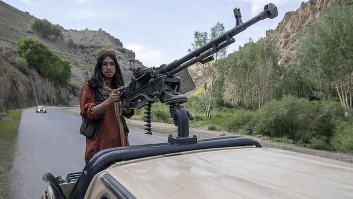 A Taliban fighter stands guard on the back of a pickup truck on a road in Wardak province, Afghanistan, Sunday, June 18, 2023. (AP Photo/Ebrahim Noroozi)