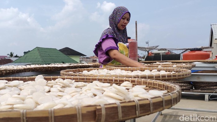 Salah satu pegawai toko kemplang dan kerupuk Rizkyanti, sedang menjemur kemplang dan kerupuk yang siap akan di produksi. (Welly Jasrial Tanjung/detikSumbagsel)