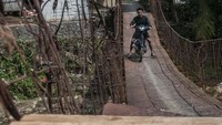 Pengendara sepeda motor melintasi jembatan gantung yang rusak di Nayagati, Lebak, Banten, Senin (19/6/2023). 