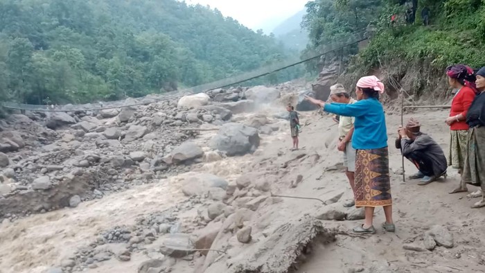 Banjir dan Longsor Melanda Nepal Timur, Puluhan Orang Hilang People stand near a site of a landslide caused due to heavy rains in Sankhuwasabha, Nepal, June 18, 2023 in this screen grab obtained from a social media video. Roman Gurung/via REUTERS THIS IMAGE HAS BEEN SUPPLIED BY A THIRD PARTY. MANDATORY CREDIT. NO RESALES. NO ARCHIVES.