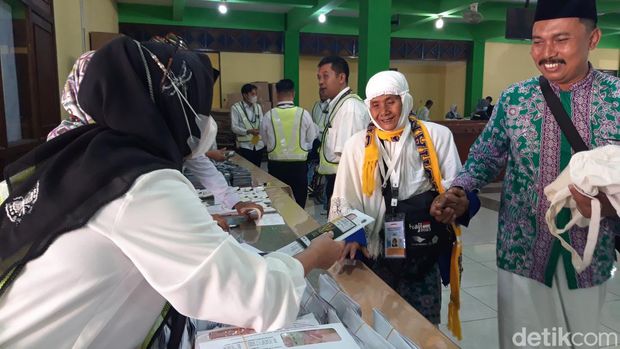 Jemaah calon haji tertua Jateng-DIY, Suminah binti Sadami, didampingi ketua rombongan, Hendro Tanoko, menerima dokumen penerbangan dari PPIH Embarkasi Solo.