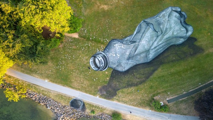 Swiss-French artist SAYPE poses in front of his land art painting representing a pet bottle left on the grass as litter in the Parc Bourget in Lausanne, Switzerland, June 16, 2023. REUTERS/Denis Balibouse