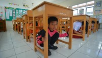 Sejumlah murid berlindung di bawah meja saat simulasi evakuasi gempa dan tsunami di SD Tirtonadi Batang Arau, Padang, Sumatera Barat, Selasa (20/6/2023).  