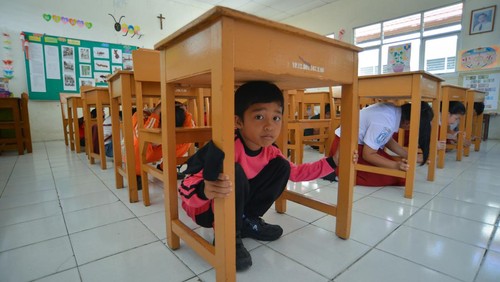 Sejumlah murid berlindung di bawah meja saat simulasi evakuasi gempa dan tsunami di SD Tirtonadi Batang Arau, Padang, Sumatera Barat, Selasa (20/6/2023). BPBD Padang menggelar sosialisasi dan simulasi evakuasi gempa dan tsunami sekaligus menetapkan gedung sekolah tersebut sebagai Tempat Evakuasi Sementara (TES) bagi anak-anak sekolah dan guru. ANTARA FOTO/Iggoy el Fitra/foc.