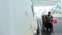 Warga melintas di samping coretan yang mengotori underpass Dewi Sartika.  