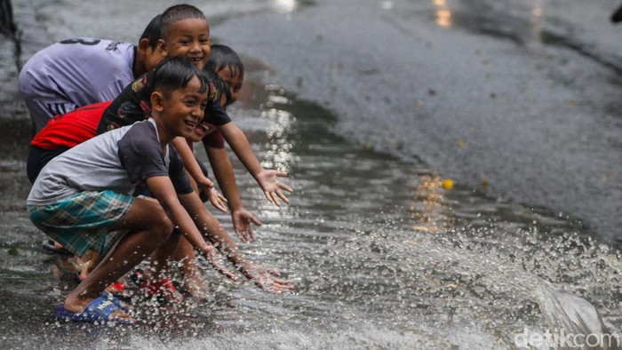 Hujan yang mengguyur kawasan Tangerang Selatan (Tangsel) membuat sejumlah jalan tergenang. Genangan air dimanfaatkan anak-anak bermain cipratan.