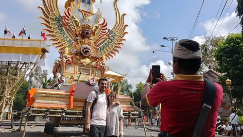 Sepasang turis asal Spanyol, Rodrigo (26) dan Maria (27) berfoto di depan perlengkapan pelebon Raja Denpasar IX, Ida Tjokorda Ngurah Jambe Pemecutan, di kawasan Catur Muka, Denpasar, Rabu (21/6/2023).