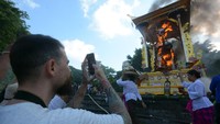 Wisatawan mancanegara menyaksikan peti berbentuk lembu yang berisi jenazah Raja Denpasar IX Ida Tjokorda Ngurah Jambe Pemecutan dibakar saat upacara Pelebon di Denpasar, Bali, Rabu (21/6/2023).  