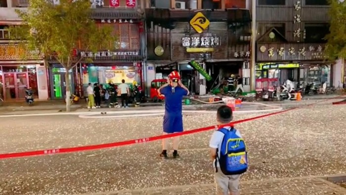 CHINA-BLAST/ A child looks at the building on fire following a gas explosion at a barbecue restaurant in Yinchuan city, Ningxia, China, on June 21, 2023 in this screengrab obtained from a handout video. Video Obtained By Reuters/Handout via REUTERS THIS IMAGE HAS BEEN SUPPLIED BY A THIRD PARTY. NO RESALES. NO ARCHIVES.