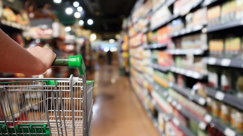 woman hand hold shopping cart with Abstract blur supermarket aisle background