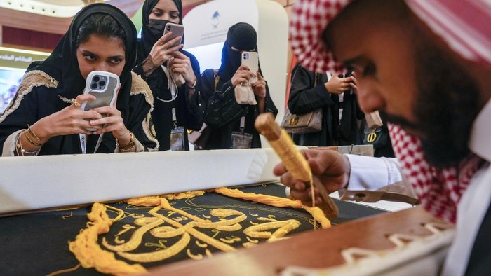 Intip Penyulaman Kiswah dengan Benang Emas Saudi Ahmed Al Humani embroiders Islamic calligraphy in the final stages of the preparation of a drape, or Kiswa, that covers the Kaaba, a cube-shaped structure at the heart the Grand Mosque, at the Media Oasis exhibition in Mecca, Saudi Arabia, Wednesday, June 21, 2023. Muslim pilgrims are converging on Saudi Arabia's holy city of Mecca for the largest hajj since the coronavirus pandemic severely curtailed access to one of Islam's five pillars. (AP Photo/Amr Nabil)