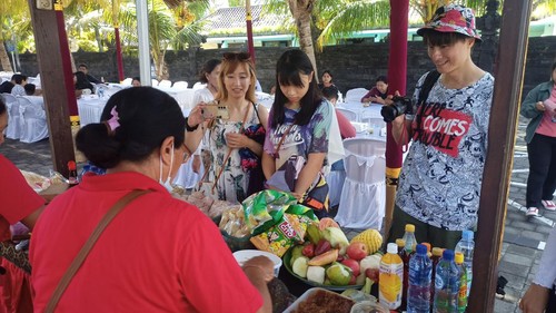 Piafin, Emily, dan Powen menantikan rujak dan tipat cantok yang dipesan pada salah satu stan kuliner tradisional di arena Festival Tanah Lot, Kamis (22/6/2023). (chairul amri simabur/detikBali)