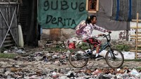 Seorang anak berangkat ke sekolah dengan melintasi sampah yang berseralan di kolong tol.  