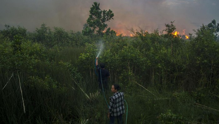 Kebakaran Lahan di Kalsel Nyari Merambati Permukiman Warga Seorang warga menggendong anaknya saat terjadi kebakaran lahan di dekat permukiman di Kecamatan Landasan Ulin, Banjarbaru, Kalimantan Selatan, Jumat (23/6/2023). Kencangnya angin di lokasi kebakaran lahan membuat api dengan cepat menyebar membakar lahan mencapai puluhan hektare dan hingga kini tim gabungan BPBD, Brimob dibantu relawan pemadam kebakaran masih berupaya memadamkan api yang mendekati permukiman penduduk. ANTARA FOTO/Bayu Pratama S/nym.