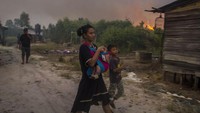 Seorang warga menggendong anaknya saat terjadi kebakaran lahan di dekat permukiman di Kecamatan Landasan Ulin, Banjarbaru, Kalimantan Selatan, Jumat (23/6/2023). 