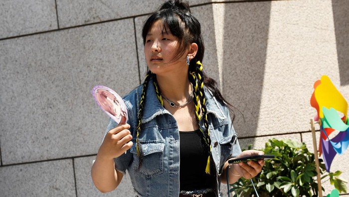 People shield themselves from the sun, as they walk amid a red alert for heatwave in Beijing, China June 23, 2023. REUTERS/Tingshu Wang