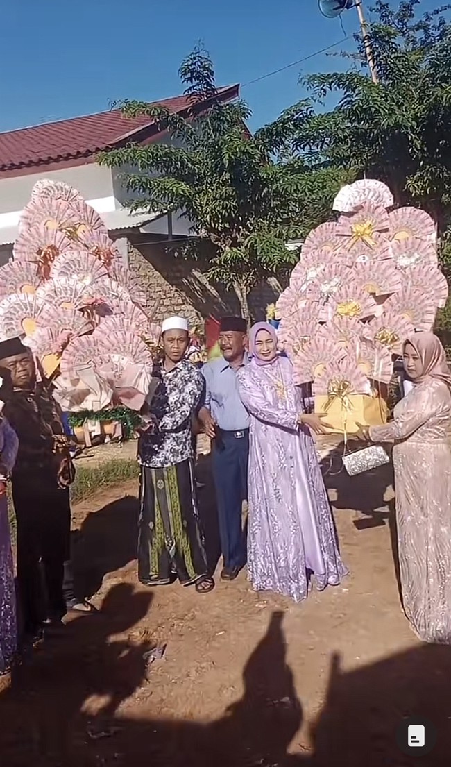 Momen penyerahan seserahan dari pengantin pria untuk pengantin wanita ini viral di media sosial. Pasalnya rombongan pengantin pria membawa buket uang bentuk kipas berukuran jumbo dan memberikan mobil baru lengkap dengan BPKB. Foto: Dok. TikTok @riyanputramadura.