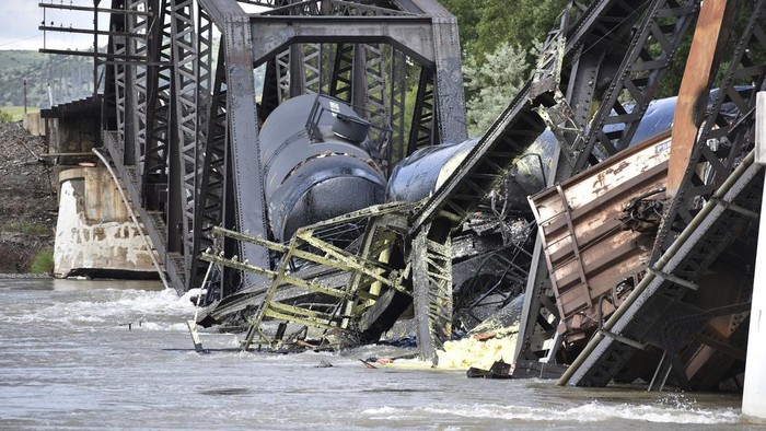 Kereta Barang Jatuh ke Sungai Yellowstone AS Imbas Jembatan Roboh Several train cars are immersed in the Yellowstone River after a bridge collapse near Columbus, Mont., on Saturday, June 24, 2023. The bridge collapsed overnight, causing a train that was traveling over it to plunge into the water below. (AP Photo/Matthew Brown)