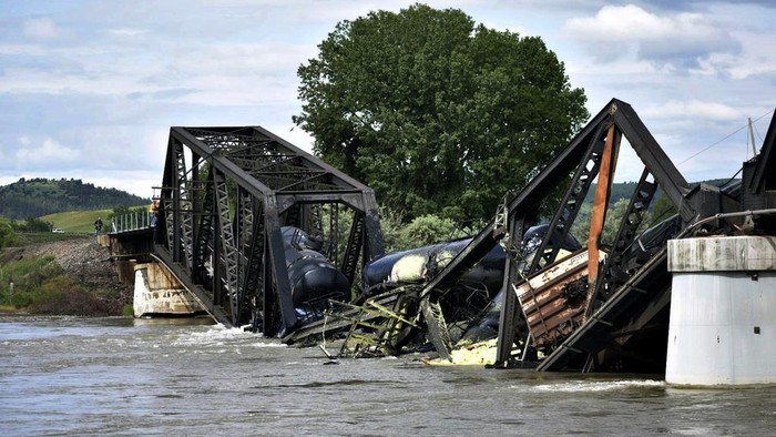 Several train cars are immersed in the Yellowstone River after a bridge collapse near Columbus, Mont., on Saturday, June 24, 2023.   The bridge collapsed overnight, causing a train that was traveling over it to plunge into the water below. (AP Photo/Matthew Brown)