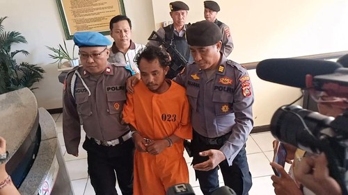 MG alias Bryan dengan tangan terborgol saat digelandang polisi di Polsek Kuta, Minggu (25/6/2023) sore. (Foto Agus Eka/detikBali)