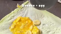 Mirip dengan martabak telur pada umumnya, isian akan diaduk dalam gelas dan dituangkan ke atas adonan kulit. Bedanya, martabak ini diisi dengan potongan pisang. Foto: TikTok/bangkokfoodie