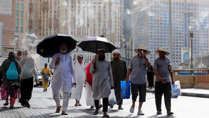 Men walk with umbrellas as people start arriving to perform the annual Haj in the Grand Mosque, in the holy city of Mecca, Saudi Arabia, June 24, 2023. REUTERS/Mohamed Abd El Ghany