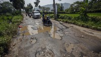 Pengendara melintasi jalan yang rusak di jalur wisata Puncak Dua, Sukamakmur, Kabupaten Bogor, Jawa Barat, Senin (26/6/2023).