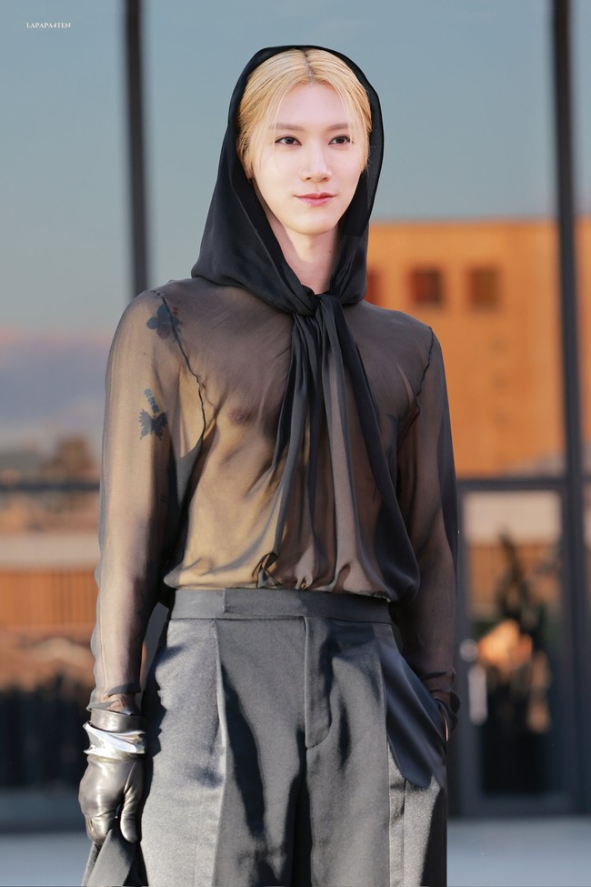 Personel NCT asal Thailand itu tampil memakai silk blouse transparan dari koleksi busana pria Saint Laurent Fall 2023. Penampilan Ten semakin misterius dengan tudung yang menutupi rambut pirangnya. Foto: Instagram