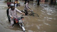 Pengendara sepeda motor melewati jalan yang tergenang air akibat hujan deras, di Lahore, Pakistan, Senin (26/6/2023).   