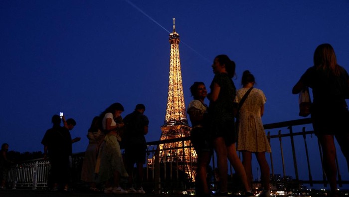 People sit on a bank of the River Seine near the Eiffel Tower in Paris, France, June 25, 2023. REUTERS/Benoit Tessier