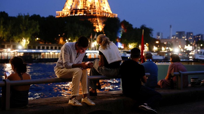 People sit on a bank of the River Seine near the Eiffel Tower in Paris, France, June 25, 2023. REUTERS/Benoit Tessier
