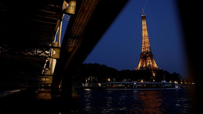 People sit on a bank of the River Seine near the Eiffel Tower in Paris, France, June 25, 2023. REUTERS/Benoit Tessier
