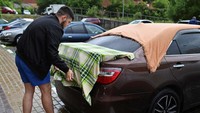 Butiran es berjatuhan mengguyur kendaraan yang terparkir. Sebagian warga pun terpaksa menutupi kendaraannya dengan kain.  
