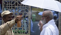 Seorang petugas polisi menyemprotkan air dingin ke seorang jemaah haji di kamp tenda Mina di Mekkah. Kementerian Kesehatan Arab Saudi merilis peringatan agar para jemaah haji mewaspadai kelelahan akibat cuaca panas ekstrem saat menjalankan ritual ibadah haji tahun ini. 