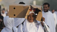 Seorang jamaah haji melindungi diri dengan kardus dari terik matahari di dekat bukit berbatu yang dikenal sebagai Gunung Rahmat, di Dataran Arafah. Suhu di Saudi dalam beberapa tahun belakangan memang sangat panas imbas pemanasan global. Per hari Senin (27/6), suhu bahkan melonjak hingga 46 derajat celsius.