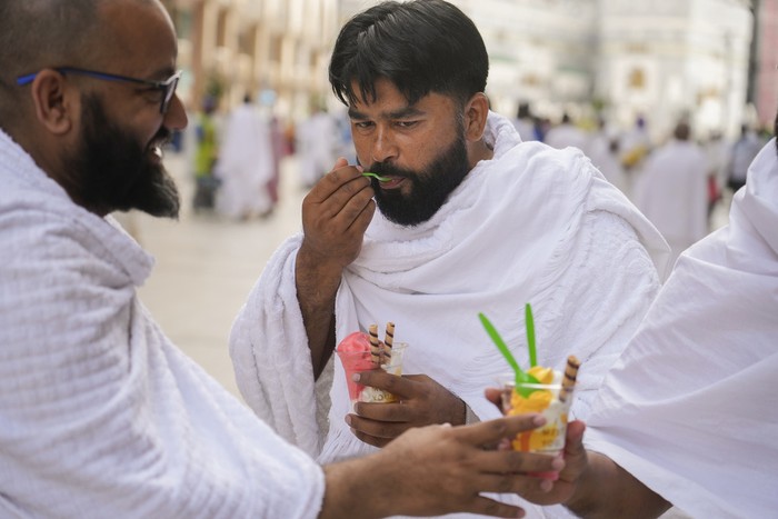 Pakistani pilgrim Muhammad Ramzan, and his friends eat ice cream outside the Grand Mosque, during the annual hajj pilgrimage, in Mecca, Saudi Arabia, Saturday, June 24, 2023. Muslim pilgrims are converging on Saudi Arabia's holy city of Mecca for the largest hajj since the coronavirus pandemic severely curtailed access to one of Islam's five pillars. (AP Photo/Amr Nabil)