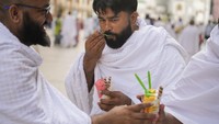 Jemaah haji makan es krim di luar Masjidil Haram, selama ibadah haji tahunan, di Mekkah. Dalam pernyataannya, Kementerian Kesehatan Saudi menekankan bahwa menggunakan payung, meminum banyak cairan, menghindari aktivitas fisik, dan mematuhi pedoman kesehatan bisa melindungi para jemaah haji dari heatstroke atau stres akibat cuaca panas ekstrem (heat stress).