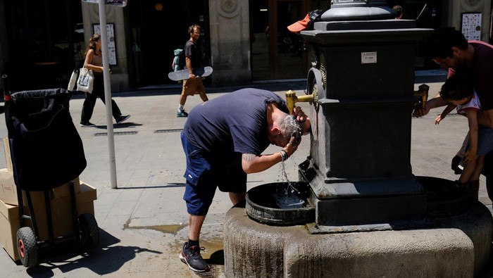 Spanyol Diterjang Gelombang Panas Ekstrem Xavi, 50, who is a door-to-door parcel delivery man, cools himself in a fountain during his work, ahead of first summer heatwave in the centre of Barcelona, Spain June 26, 2023. REUTERS/Nacho Doce