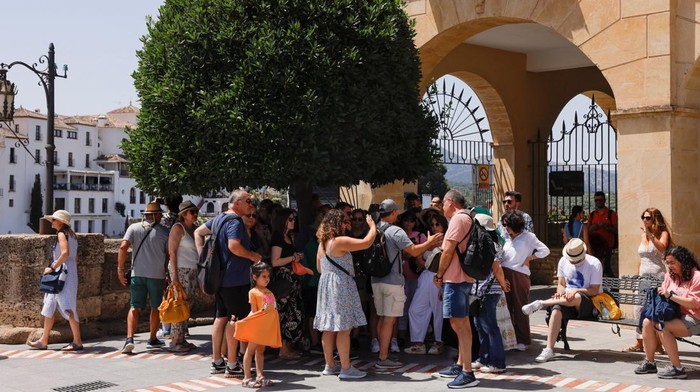 Locals and tourists walk under the shadow to avoid the sun during the hottest hours of the day, at a shopping street during the first day of the first heatwave of the summer in downtown Ronda, Spain, June 25, 2023. REUTERS/Jon Nazca