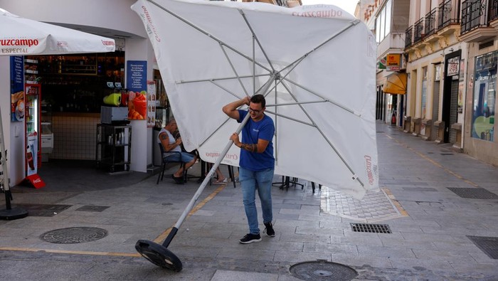 Locals and tourists walk under the shadow to avoid the sun during the hottest hours of the day, at a shopping street during the first day of the first heatwave of the summer in downtown Ronda, Spain, June 25, 2023. REUTERS/Jon Nazca