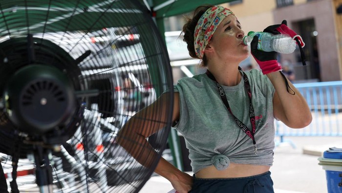 Cristina Zambrana takes a water break from work while she and her crew dismantle equipment following a fun fair in, as the Spanish weather agency AEMET expects the country to experience a heatwave, in Madrid, Spain, June 25, 2023. REUTERS/Isabel Infa