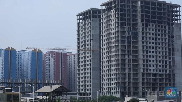 Warga melewati bangunan Apartemen Point 8 yang terbengkalai di kawasan Daan Mogot, Jakarta, Selasa (27/6/2023). (CNBC Indonesia/Tri Susilo)