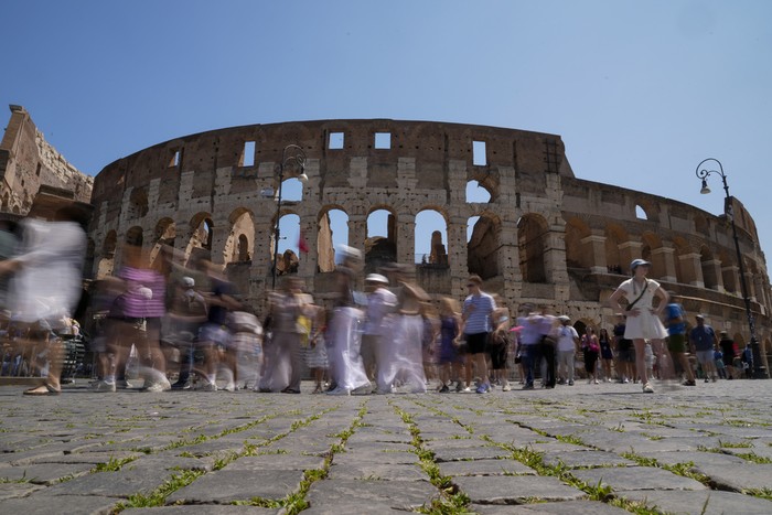 Visitors walk past the Colosseum, in Rome, Tuesday, June 27, 2023. Italys culture and tourism ministers Gennaro Sangiuliano vowed to find and punish a tourist who was filmed carving his name and his girlfriends name in the wall of the Colosseum, a crime that in the past has resulted in hefty fines. Video of the incident went viral on social media, at a time when Romans have already been complaining about hordes of tourists returning to peak season travel this year. (AP Photo/Andrew Medichini)
