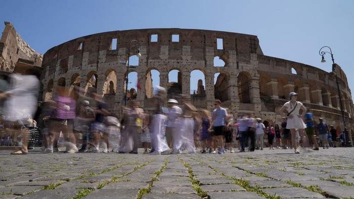 Visitors walk past the Colosseum, in Rome, Tuesday, June 27, 2023. Italys culture and tourism ministers Gennaro Sangiuliano vowed to find and punish a tourist who was filmed carving his name and his girlfriends name in the wall of the Colosseum, a crime that in the past has resulted in hefty fines. Video of the incident went viral on social media, at a time when Romans have already been complaining about hordes of tourists returning to peak season travel this year. (AP Photo/Andrew Medichini)