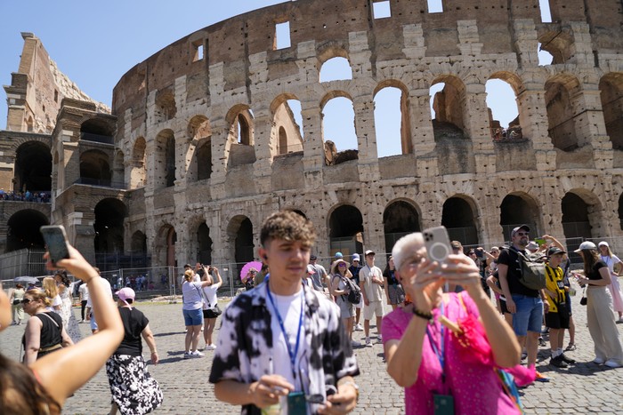Visitors walk past the Colosseum, in Rome, Tuesday, June 27, 2023. Italys culture and tourism ministers Gennaro Sangiuliano vowed to find and punish a tourist who was filmed carving his name and his girlfriends name in the wall of the Colosseum, a crime that in the past has resulted in hefty fines. Video of the incident went viral on social media, at a time when Romans have already been complaining about hordes of tourists returning to peak season travel this year. (AP Photo/Andrew Medichini)
