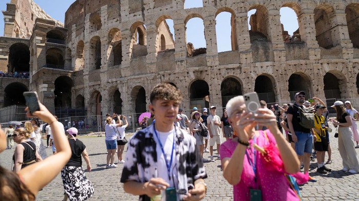 Visitors walk past the Colosseum, in Rome, Tuesday, June 27, 2023. Italys culture and tourism ministers Gennaro Sangiuliano vowed to find and punish a tourist who was filmed carving his name and his girlfriends name in the wall of the Colosseum, a crime that in the past has resulted in hefty fines. Video of the incident went viral on social media, at a time when Romans have already been complaining about hordes of tourists returning to peak season travel this year. (AP Photo/Andrew Medichini)