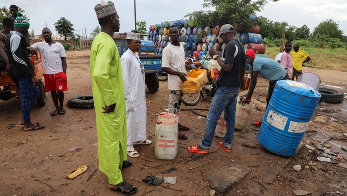 Nigeria Hapus Subsidi BBM Bikin 'Satu Benua' Sengsara Yaouba Ahmadou, in white dress, a semi-wholesaler of Nigeria's contraband fuel speaks with his workers in Garoua, Cameroon June 21, 2023. REUTERS/Desire Danga Essigue